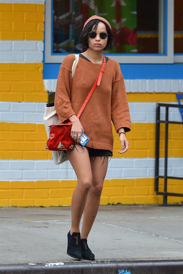Zoe Kravitz walking in shorts and an orange top