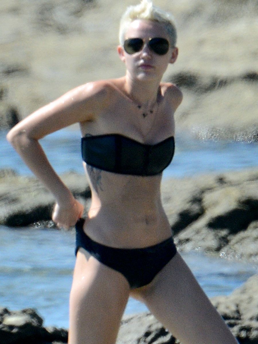 Miley Cyrus yoga in black bikini on beach in Hawaii 1/24/13. 