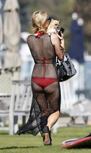 Paris Hilton at the beach in a skimpy red bikini and fishnet kaftan in Malibu.July 12, 2013