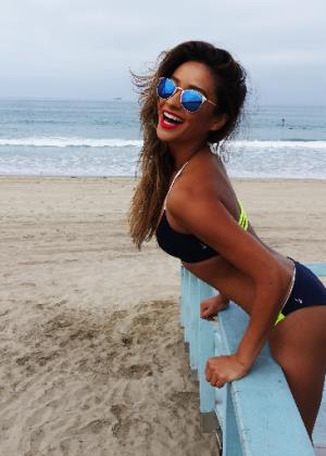 Shay Mitchell at the beach with a surfboard
