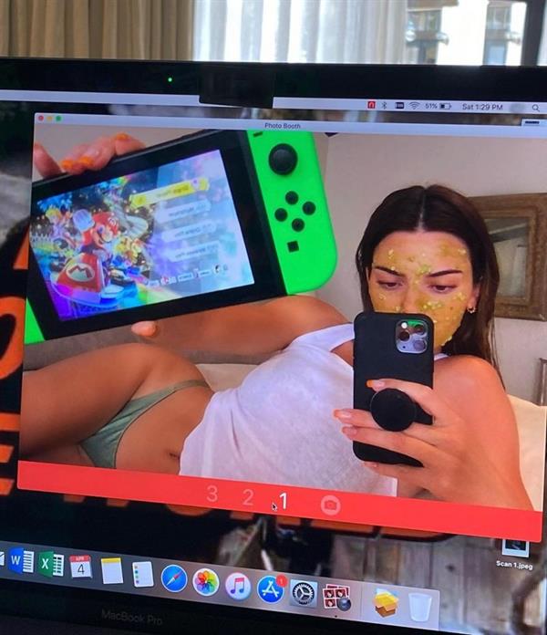 Kendall Jenner braless boobs in a white tank top playing video games to pass the time in isolation in thong panties.