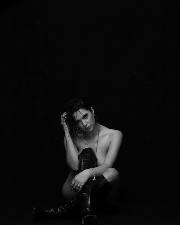Ashley Benson shared a nude throwback black and white photo sitting naked wearing only boots covering her boobs.