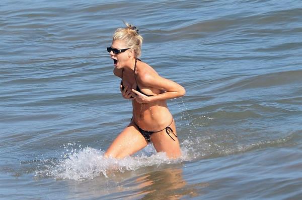 Charlotte McKinney pussy slip wardrobe malfunction in a sexy little thong bikini running out of the water holding her big tits.